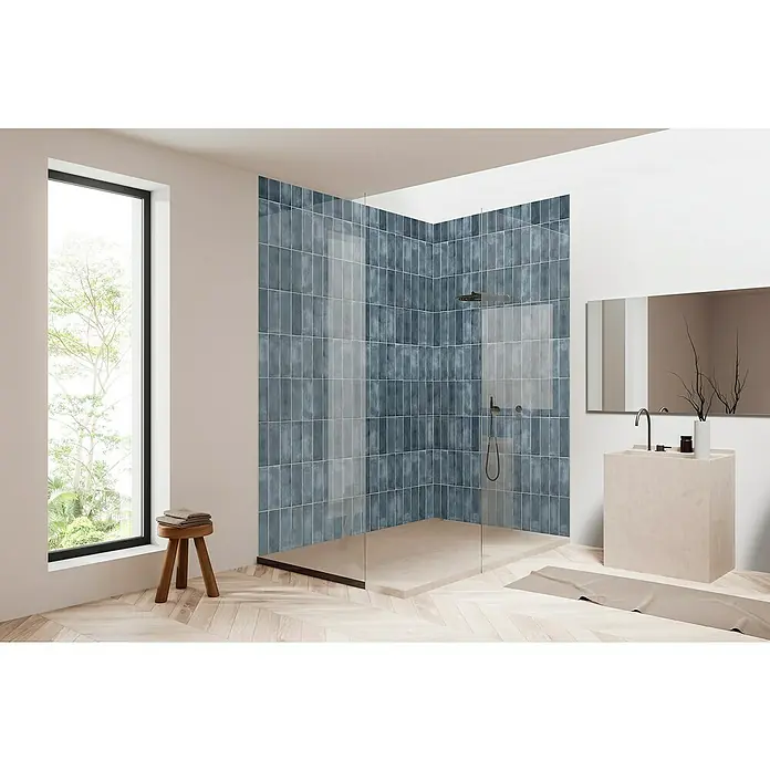 Bariperfil Panel de pared Corewall Merlin - 258 x 102,3 cm, Azul - Baño con ducha a ras de suelo con azulejos azules y mampara de cristal, suelos de madera clara y lavabo con espejo.