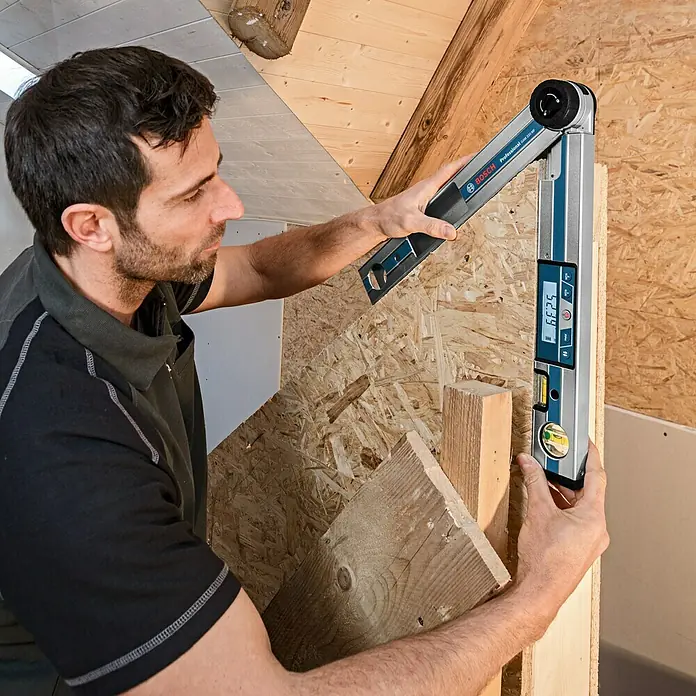 Bosch Professional Digitaler Winkelmesser GAM 220 MF - Messbereich: 0 - 220 °, Schenkellänge: 40 cm - Mann mit digitalem Winkelmesser von Bosch zum Messen eines Holzrahmens. Das Werkzeug zeigt einen Winkel von 52,39 Grad an.