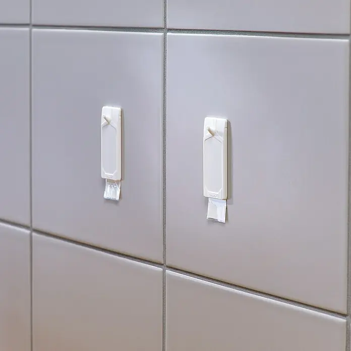 Tesa Klebenagel - Geeignet für: Fliesen, Belastbarkeit: 3 kg, 2 Stk., Weiß - Zwei weiße Tesa Powerstrips Haken auf grau gefliesten Wand, ideal für Badezimmerutensilien oder Dekoration.