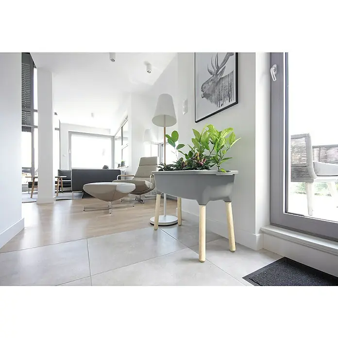 Hochbeet Respana Wood - Steingrau, 38 x 77 x 79,5 cm, Kunststoff - Das Bild zeigt einen grauen Blumenkasten auf Holzbeinen mit grünen Pflanzen in einem modernen Wohnraum.