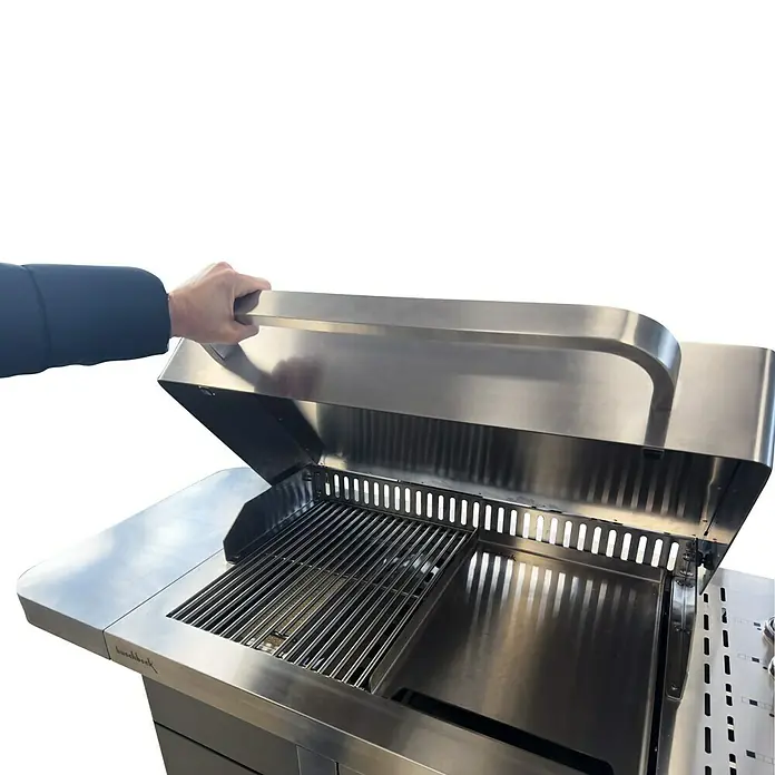 Buschbeck Gasgrill P1000 - 3,5 kW, Anzahl Brenner: 4 Stk. - Nahaufnahme eines Edelstahl-Gasgrills mit geöffnetem Deckel, bedient von einer Hand, wodurch die Grillroste sichtbar werden.