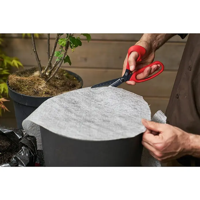 Felco Universalschere 455 - Länge: 28,5 cm - Ein Gärtner schneidet mit einer roten Schere ein Stück Unkrautvlies zurecht, um es in einen Pflanztopf zu legen.