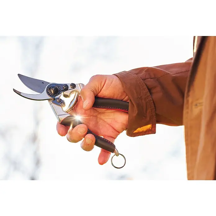 Felco Gartenschere 8 Elite - Bypass, Max. Aststärke: 25 mm - Nahaufnahme einer Hand, die eine hochwertige Gartenschere mit schwarzen Griffen und Metallelementen hält.\n