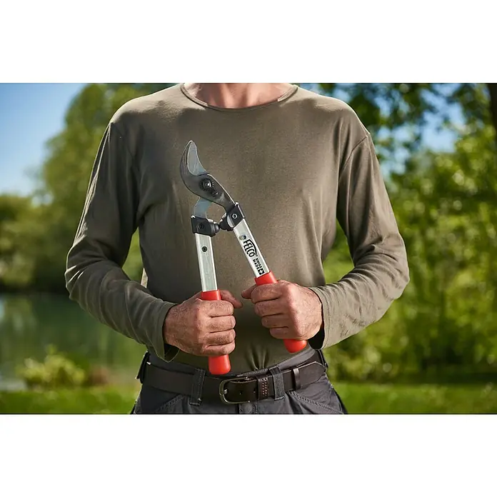 Felco Astschere 211-40 - Max. Aststärke: 35 mm, Länge: 40,5 cm - Eine Person hält eine Felco Baumschere mit roten Griffen vor dem Körper, ideal für präzise Baumschnitte.