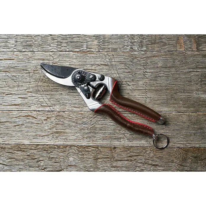 Felco Gartenschere 8 Elite - Bypass, Max. Aststärke: 25 mm - Nahaufnahme einer Felco-Gartenschere mit braunen Griffen und roten Akzenten auf einer strukturierten Holzoberfläche.