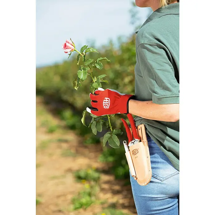 Felco Holster 910+ - Passend für: Felco Baum-, Reb-, Gartenscheren und Schleifstein 903 - Nahaufnahme einer Frau mit Felco-Gartenhandschuhen, einer Gartenschere und einer Rose.