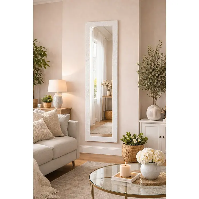 Espejo de pared Milán - 53,5 x 155,5 cm, Blanco/gris - Un espejo de cuerpo entero con marco blanco cuelga en una pared de la sala de estar, reflejando la luz natural. El espejo ilumina la habitación.