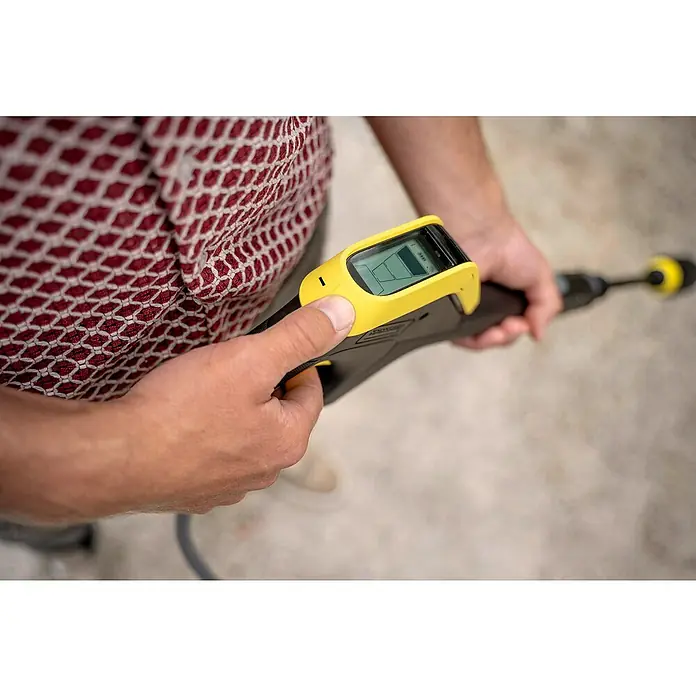 Kärcher Hochdruckreiniger K 7 Comfort Premium Connect Home - 3.000 W, Max. Druck: 180 bar, Fördermenge: 600 l/h, Inkl. Home-Kit - Nahaufnahme eines Mannes, der eine Kärcher Hochdruckreiniger-Pistole mit Display hält und bedient. Das Gerät ist schwarz mit gelben Akzenten.