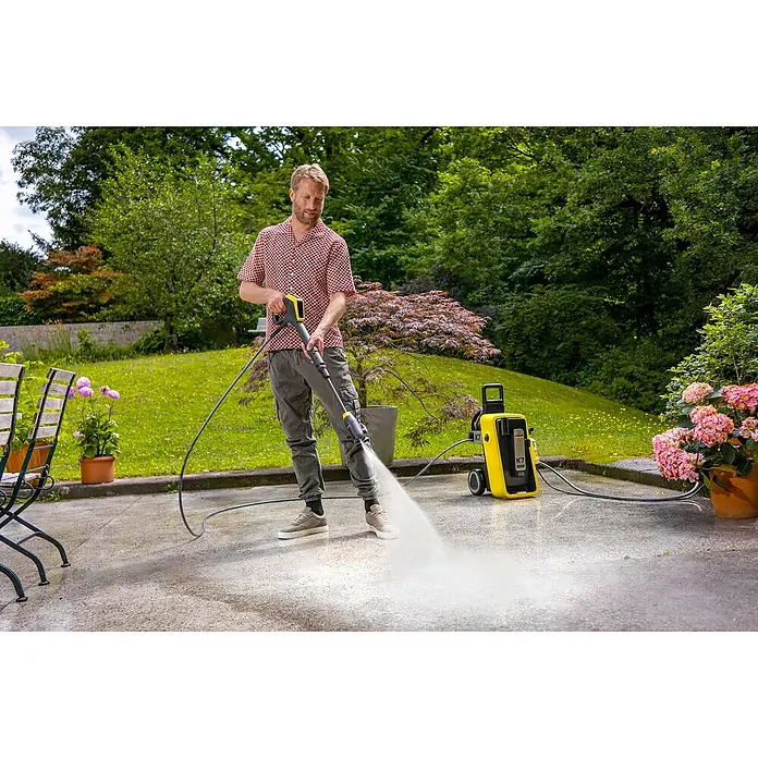 Kärcher Hochdruckreiniger K 7 Comfort Premium Connect Home - 3.000 W, Max. Druck: 180 bar, Fördermenge: 600 l/h, Inkl. Home-Kit - Ein Mann benutzt einen Kärcher K7 Hochdruckreiniger, um eine Terrasse zu reinigen. Der Reiniger ist gelb und schwarz und steht auf der Terrasse.