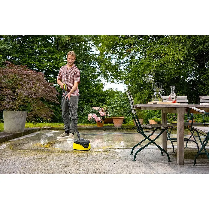 Kärcher Hochdruckreiniger K 7 Comfort Premium Connect Home - 3.000 W, Max. Druck: 180 bar, Fördermenge: 600 l/h, Inkl. Home-Kit - Mann reinigt Terrasse mit Kärcher Flächenreiniger. Effektive und schonende Reinigung von Außenbereichen mit dem gelben Gerät.
