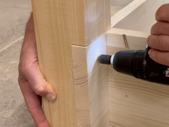 Holzplatten werden an einen Pfosten mit Schrauben befestigt