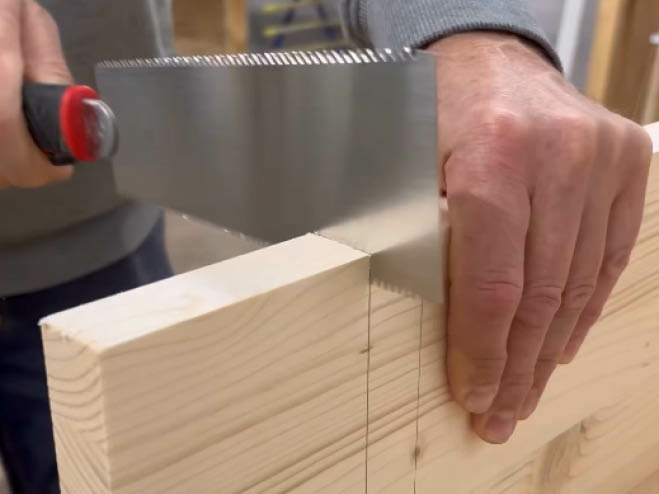 Mit der Japansäge wird ein kleiner Teil von der Holzplatte weggeschnitten