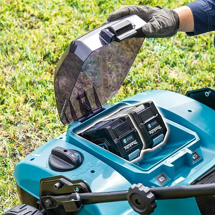 Makita XGT 40V max. Akku-Vertikutierer UV001GZ - Anzahl Akkus: Ohne Akku, 40 V, Arbeitsbreite: 38 cm - Aufsicht auf einen Makita Rasenmäher mit zwei Akkus. Die transparente Abdeckung wird von einer behandschuhten Hand geöffnet.