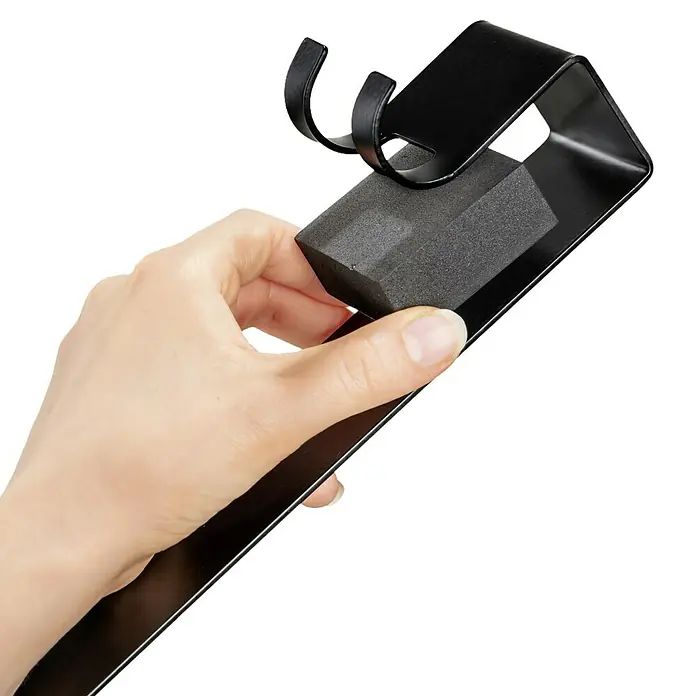 Wenko Duschkorb Bribano UNO - 18 x 23 x 44,5 cm, Schwarz - Eine Hand hält einen schwarzen Gardinenstangenhalter, der mit einem Schaumstoffteil gereinigt wird. Ideal für die Fensterdekoration.