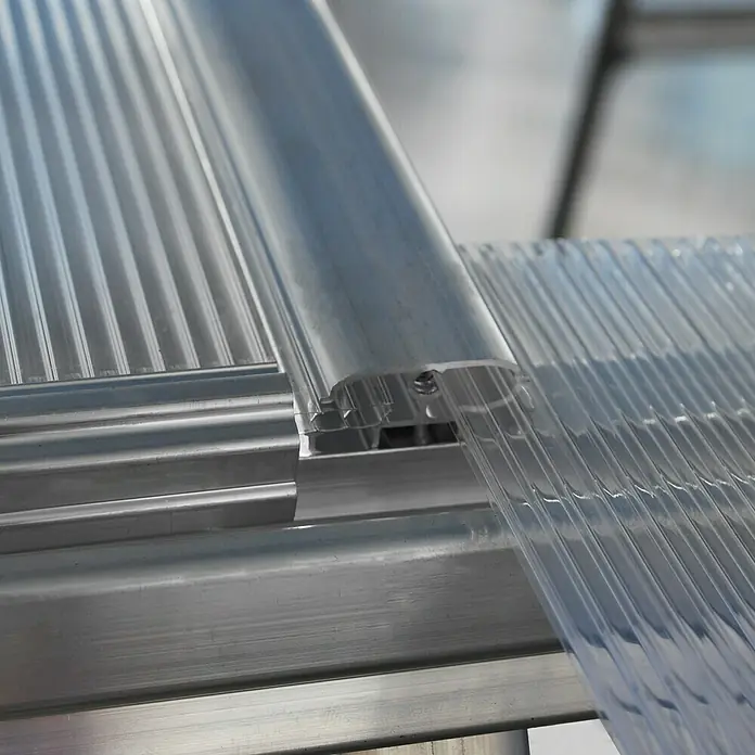 Palram – Canopia Gewächshaus Hybrid - Außenmaß inkl. Dachüberstand (B x T): 185 x 426 cm, 0,7 mm, Silber - Nahaufnahme einer transparenten, gewellten Polycarbonatplatte, die mit einem Aluminiumprofil verbunden ist und ein stabiles, modernes Design zeigt.
