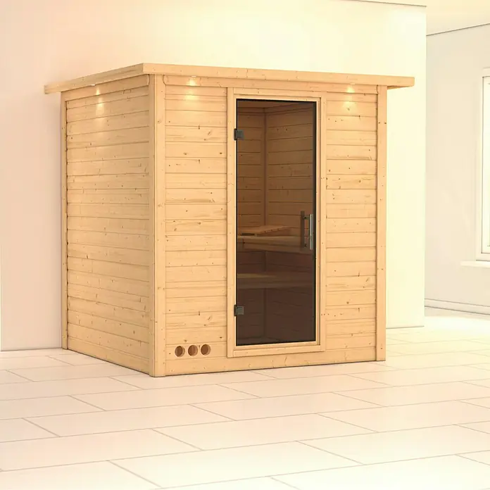 Karibu Elementsauna Mojave - Ohne Ofen, Mit Dachkranz und Beleuchtung, Materialspezifizierung Tür: Ganzglas Graphit, L x B x H: 224 x 210 x 192 cm - Diese Aufnahme zeigt eine hölzerne Sauna mit Glastür, die ein entspannendes Wellness-Erlebnis verspricht. Sie ist vor einer hellen Wand aufgestellt.