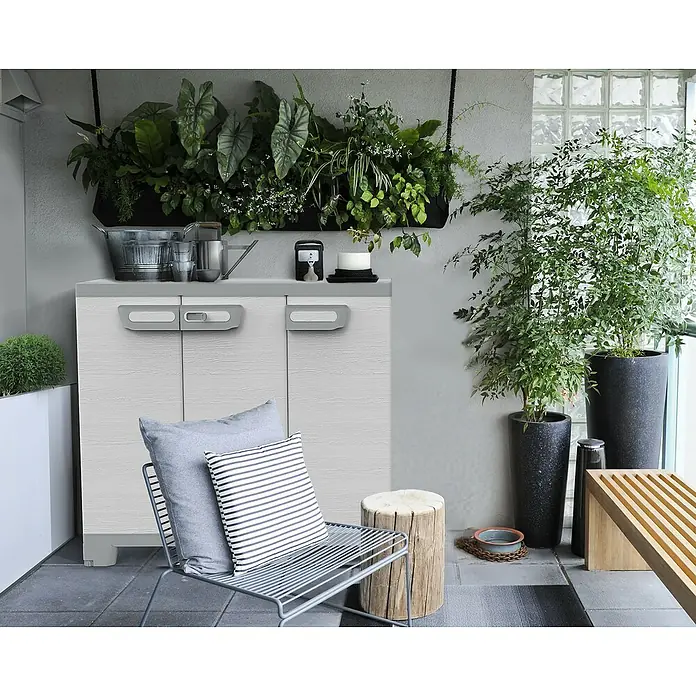 Terry Kunststoff-Mehrzweckschrank CAB 102B SEQUOIA - H x B x T: 93,5 x 102 x 39 cm, Weiß - Außenaufnahme eines weißen Outdoor-Aufbewahrungsschranks mit grauem Griff, umgeben von Pflanzen und Dekorationen.