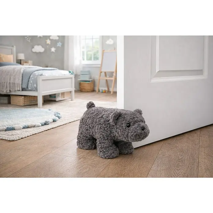 Versa Tope de puerta Oso - L x An x Al: 29 x 12 x 18 cm, Gris - Un tope de puerta gris en forma de perro de ganchillo se inclina contra una puerta blanca, manteniéndola abierta. Dulce decoración para una habitación infantil.