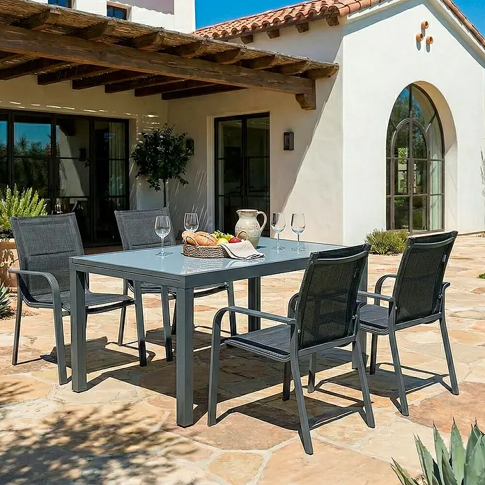 Sunfun Anna Sillón de jardín Anna - 56,5 x 67 x 91,5 cm, Antracita, Acero/Textiline - Un conjunto de comedor exterior gris con mesa y sillas en un patio, perfecto para cenar y relajarse al aire libre.