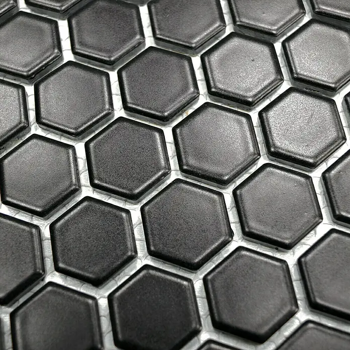 Mosaikfliese Hexagon Uni HX 065 - 26 x 30 cm, Schwarz, Matt - Nahaufnahme von schwarzen, matten sechseckigen Fliesen mit weißen Fugen, die ein modernes und elegantes Design für Innenräume bieten.