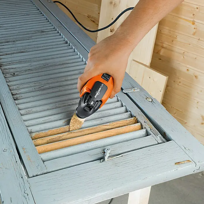 Fein Starlock Plus Hartmetall-Raspel - Fingerform, Beidseitige Beschichtung - Nahaufnahme eines oszillierenden Multifunktionswerkzeugs zum Schleifen einer Fensterluke.