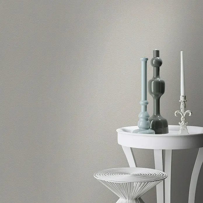 Rasch Vliestapete - Braun/Erdtöne/Taupe, Uni, 10,05 x 0,53 m, Feine Struktur - Dekorative Kerzen und Vasen auf einem weißen Tisch. Die graue Wand sorgt für einen neutralen Hintergrund.