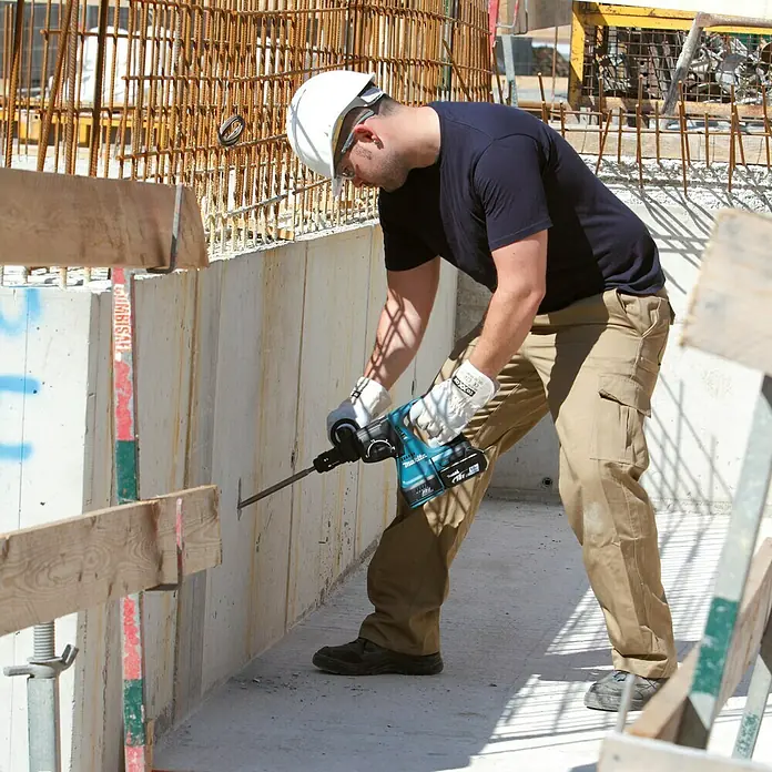 Makita LXT 18V Akku-Kombihammer DHR243RTJ - 18 V, 2 Akkus, 5 Ah, 2 J, Ohne Staubabsaugung - Bauarbeiter mit Makita Bohrhammer bei der Arbeit auf einer Baustelle. Der Akku-Bohrhammer ist ideal für schwere Bohrarbeiten in Beton.