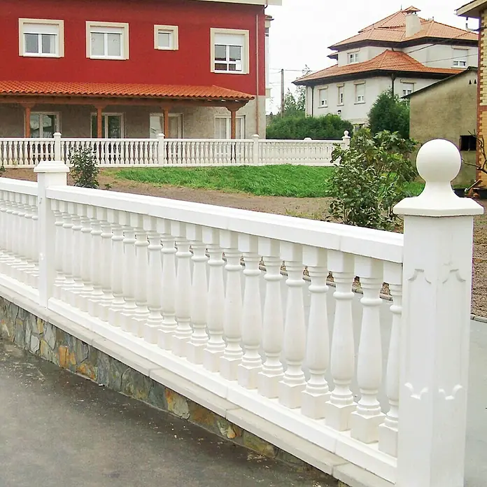 Columna decorativa Milan 2 - 20 cm x 1,2 m, Blanco - Primer plano de una valla de balaustrada blanca con pilares decorativos y cimiento de piedra, delimitando una propiedad.