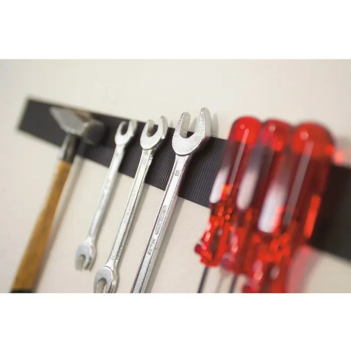 Tesa ON & OFF Cinta de velcro Extra Fuerte - 50 mm x 1 m - Primer plano de un soporte magnético para herramientas con un martillo, llaves inglesas y destornilladores para la organización del taller.