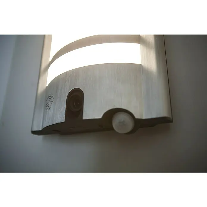 Aplique exterior LED con sensor y cámara HD VESTA - 30 W, L x An x Al: 11 x 26 x 40 cm, Blanco cálido - Primer plano de una lámpara de pared moderna con cámara integrada y sensor de movimiento, montada en una pared clara.