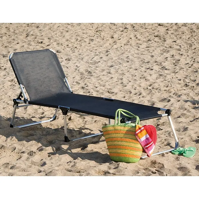 Siena Garden Gartenliege XXL - Schwarz, Aluminium, Rückenlehne verstellbar - Eine schwarze Strandliege aus Metall auf Sand, daneben eine gestreifte Tasche, ein Handtuch und Flip-Flops.