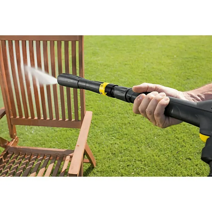 Kärcher Boquilla de alta presión Multi-Power-Jet - 5 patrones de aerosol, Específico para: Hidrolimpiadoras de alta presión Kärcher K3 - K5 - Se utiliza una hidrolimpiadora para limpiar una silla de madera para exteriores. El dispositivo es negro con detalles amarillos.