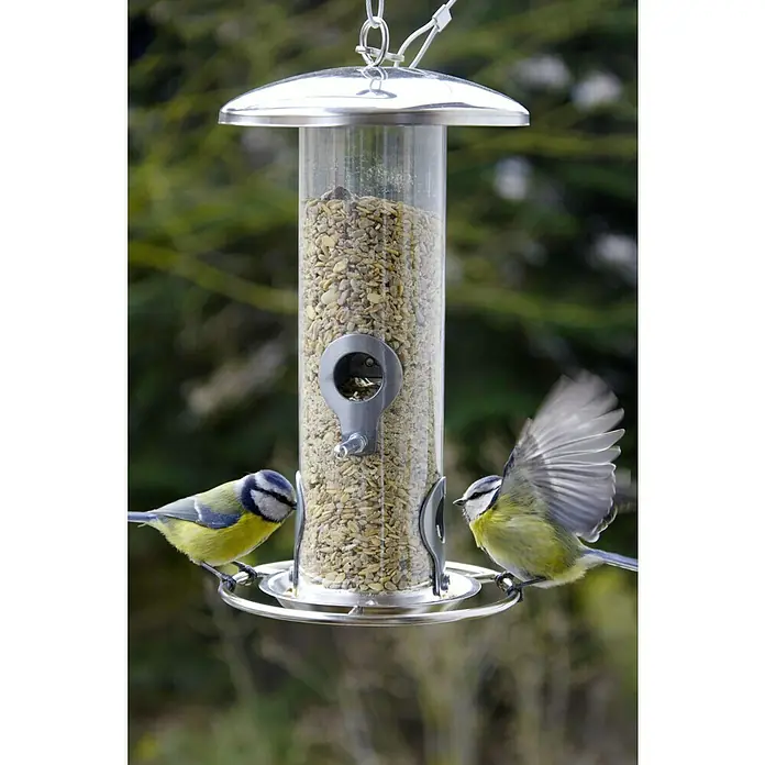 Dobar Futtersäule - Ø x H: 14 x 26 cm, Metall, Silber - Ein voller Vogelfutterspender mit zwei Blaumeisen, eine davon im Flug, im Garten.