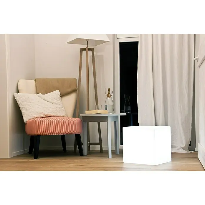 8 Seasons Design Shining LED-Dekoleuchte Cube - 6 W, Weiß, L x B x H: 33 x 33 x 33 cm - Ein moderner Raum mit einem auffälligen, leuchtenden Würfel als Lampe, der neben einem Sessel und einem kleinen Tisch steht.