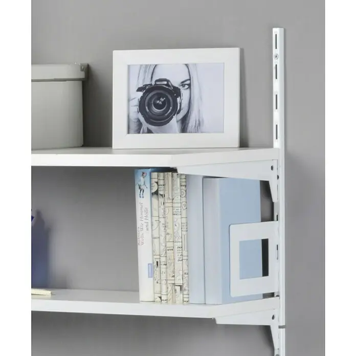 Element System Bücherbügel - 11,8 x 14,3 cm, Geeignet für: Schiene Classic Raster 50, Weiß - Nahaufnahme eines weißen Regalsystems mit diversen Gegenständen wie Bücher und einem gerahmten Bild einer Frau mit Kamera.