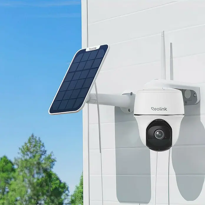 Reolink Überwachungskamera Argus Series B430 inkl. Solarpanel -  - Eine Reolink Überwachungskamera mit Solarpanel an einer weißen Wand vor blauem Himmel und Bäumen.