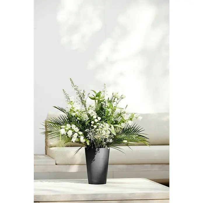 Ecopots Vase Pisa - Ø x H: 17,8 x 25,2 cm, Kunststoff, Dunkelgrau - Elegantes Arrangement aus weißen Blumen und grünen Blättern in einer stilvollen, dunklen Vase auf einem Tisch. Ideal für eine moderne Dekoration.