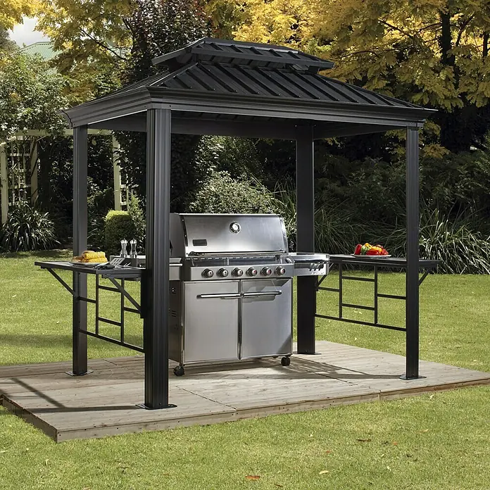 Sojag Grillpavillon Messina BBQ - B x T: 292 x 179 cm, Farbe Gestell: Anthrazit, Aluminium - Bild von einem schwarzen Grillpavillon mit einem Edelstahlgrill und Ablagetischen auf einer Holzplattform.