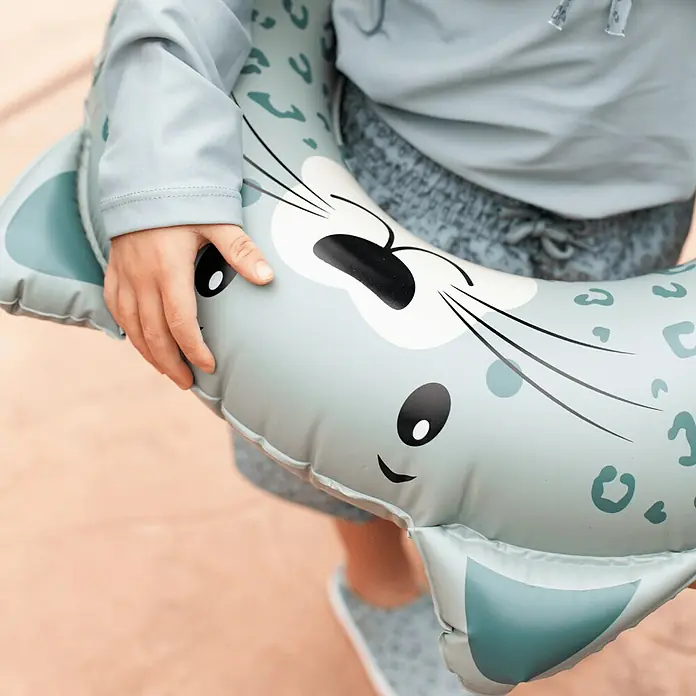 Swim Essentials Schwimmring - Durchmesser: 55 cm, Leopard - Nahaufnahme eines Kindes, das einen grauen, aufblasbaren Seehund mit niedlichem Design hält, perfekt für Wasserspaß.