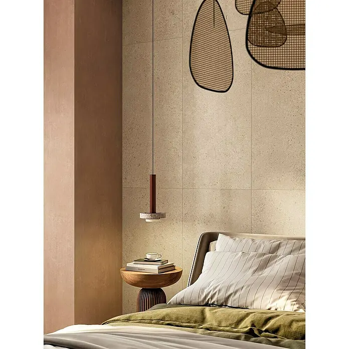 Atlas Concorde Solution Feinsteinzeugfliese Lunastone - 60 x 120 cm, Sand, Matt - Elegante Schlafzimmeransicht mit einem stilvollen Nachttisch, darauf Büchern und einer Tasse, beleuchtet von einer modernen Pendelleuchte.