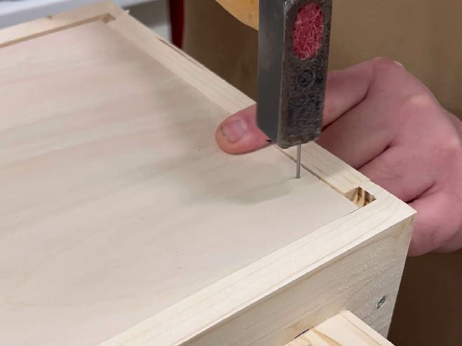 Ein Nagel wird an die Seite der Rückwand geschlagen