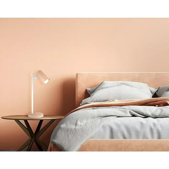 Globo Tischleuchte Robby - 5 W, L x B x H: 132 x 120 x 350 mm, Pfirsichfarben, Weiß, GU10 - Nahaufnahme einer modernen Nachttischlampe in einem stilvollen Schlafzimmer. Die Lampe strahlt ein sanftes Licht aus und erhellt den Raum.