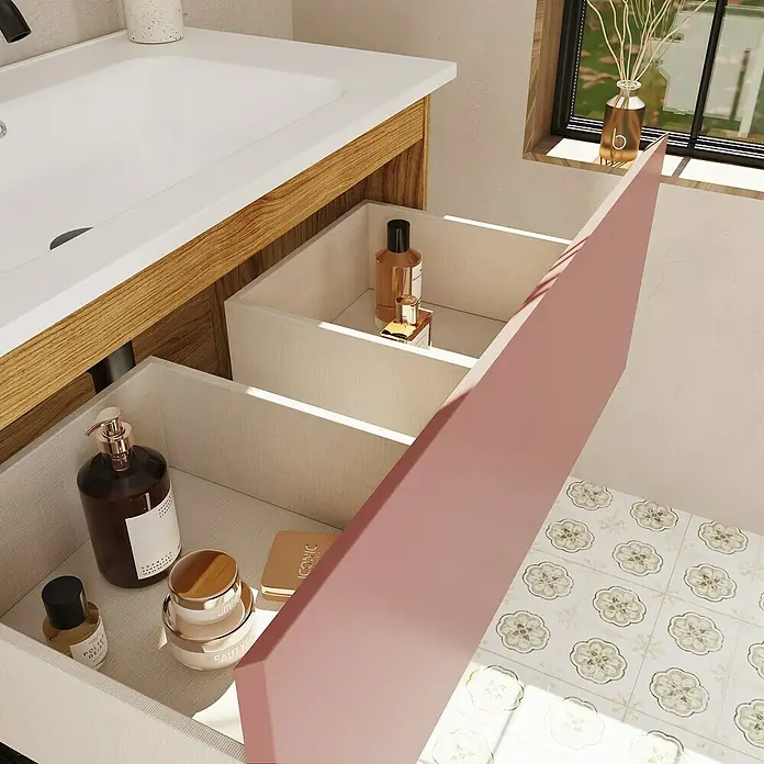 Mueble bajo de lavabo Open - An x Pr x Al: 80 x 43 x 64 cm, Rosa - Un tocador de baño con un cajón abierto revela productos cosméticos, incluyendo frascos y tarros, sobre un suelo de baldosas florales claro.