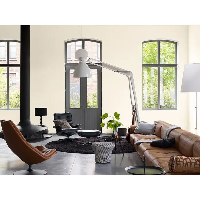 Bruguer Elegance Pintura para paredes - Blanco elegante, Mate, 4 l - Interior de salón con sofá de cuero marrón, sillones, chimenea moderna y gran lámpara de arco para un ambiente elegante.