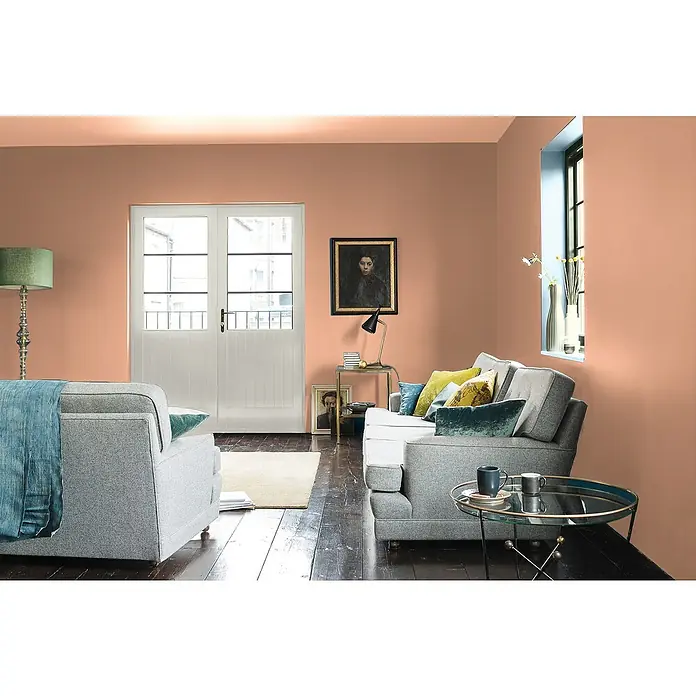 Bruguer Elegance Pintura para paredes - Terracota rústica, Mate, 4 l - Sala de estar con paredes color melocotón, sofás grises, mesa de centro y ventana con marco azul para un ambiente acogedor.