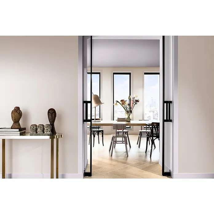 Bruguer Elegance Pintura para paredes - Rosa boho, Mate, 4 l - Un interior elegante con una mesa minimalista, sillas y elementos decorativos, visto a través de una puerta elegante.