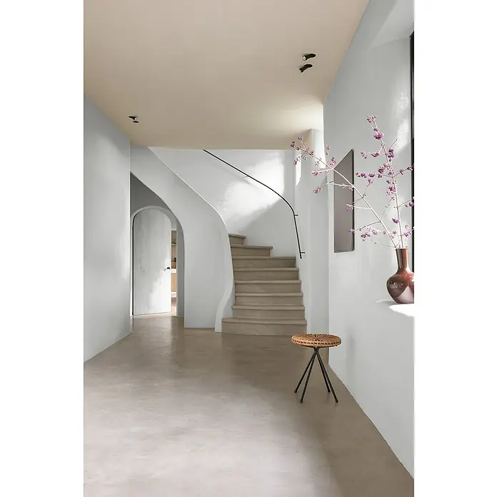 Bruguer Elegance Pintura para paredes - Gris pluma, Mate, 4 l - La imagen muestra un interior elegante de inspiración escandinava con una escalera de caracol y un taburete tejido, mostrando un diseño minimalista.