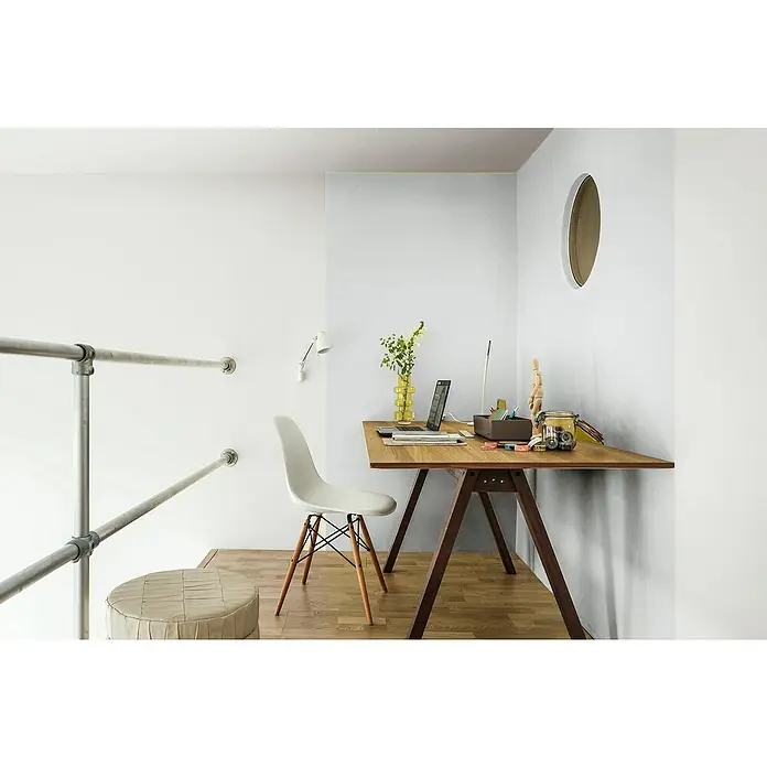 Bruguer Elegance Pintura para paredes - Gris brisa, Mate, 4 l - Escritorio de madera con patas en forma de A, computadora portátil, jarrón y adornos contra un fondo blanco. Elegante espacio de trabajo con toques modernos.