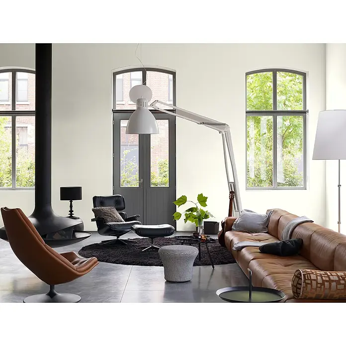 Bruguer Elegance Pintura para paredes - Beige arena, Mate, 4 l - Salón con un cómodo sofá de cuero, sillones y una moderna lámpara de pie. La decoración es elegante y acogedora.