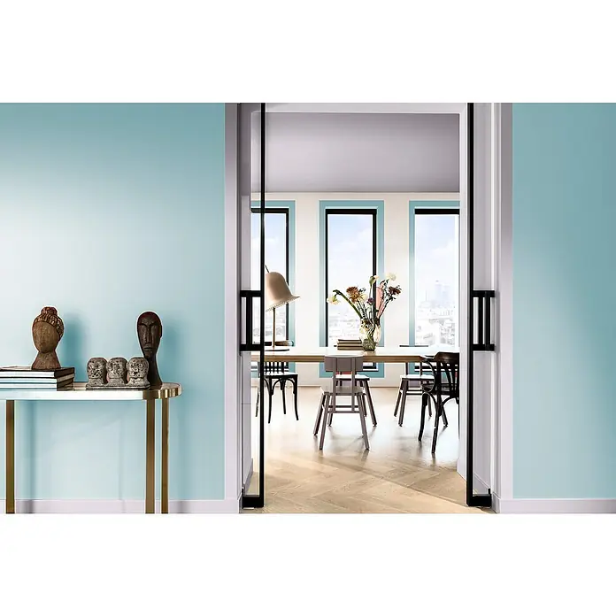 Bruguer Elegance Pintura para paredes - Azul aqua, Mate, 4 l - Habitación acogedora con paredes azules, decorada con objetos de arte sobre una mesa consola dorada, que ofrece una vista a un comedor luminoso.